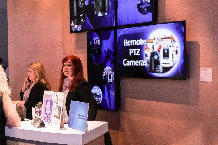 Mosaic video wall powered by Userful at Infocomm 2018, with two women from a partner company at the booth