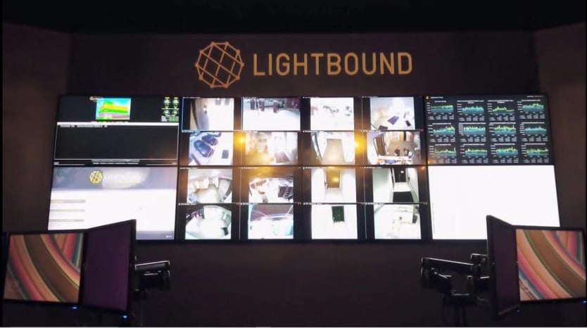 Empty Lightbound control room with 2 workstations and video wall displaying websites, data, and advertisement