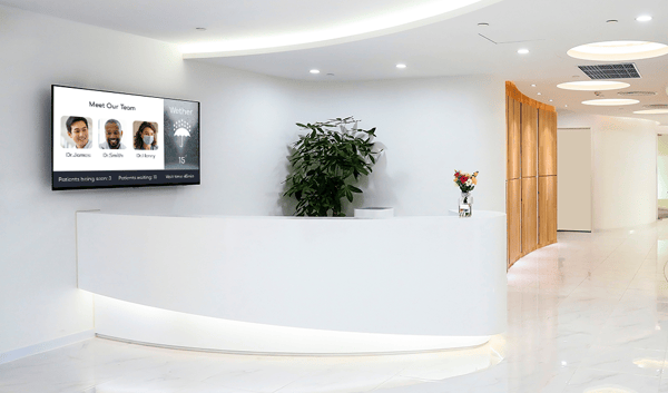 Front Desk of waiting area, with screen behind it with wait times, doctor information, and wether