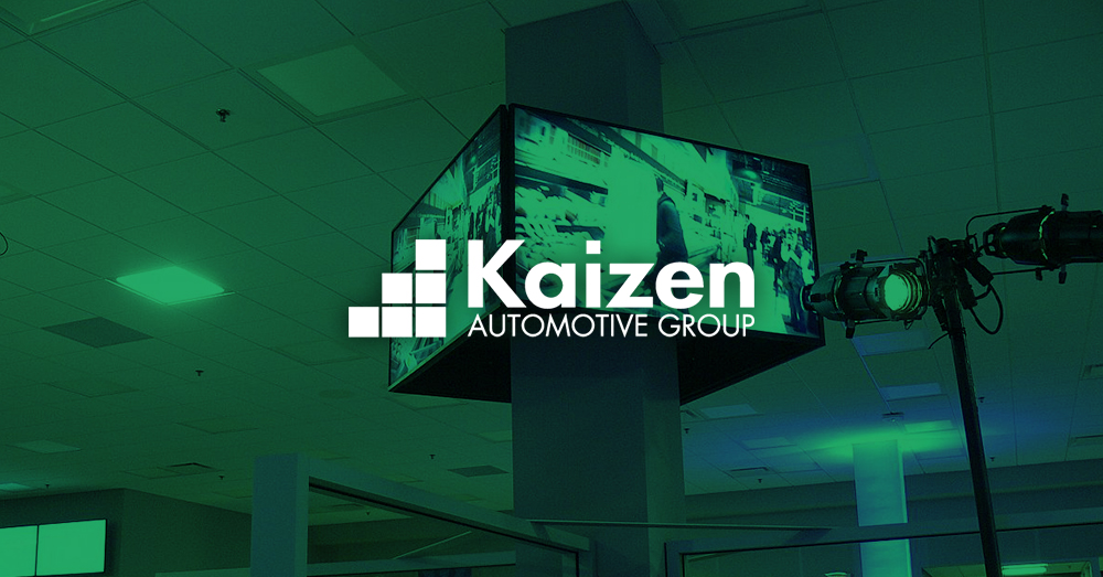 Video wall displaying car advertisement in a Kaizen Automotive Group owned dealership with green overlay and logo