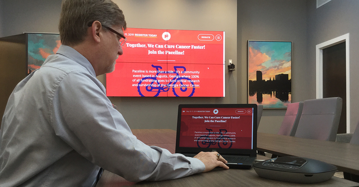 Medical College of Georgia meeting room, with a man using his laptop and Userful to display a webpage onto a video wall behind him