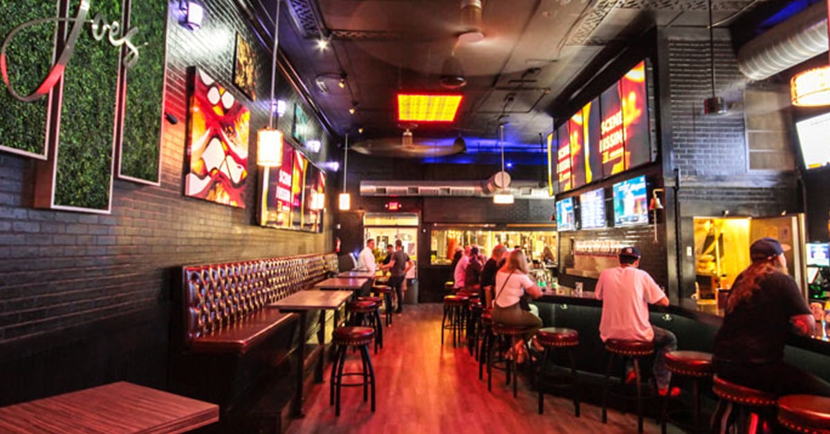 Inside Smokin' Joe's Sports Bar sitting area, customers sitting on barstools, artistic video walls that look like windows