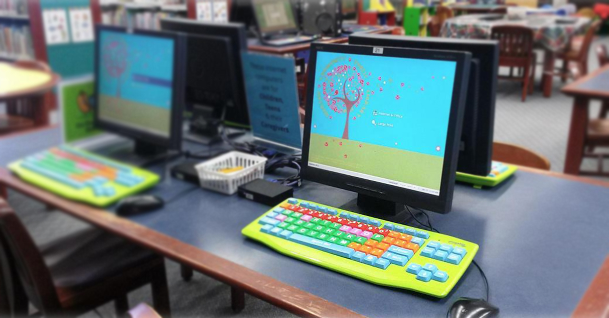 A table in the Warsaw Community public library with computers using Userful Desktop, and colourful keyboards