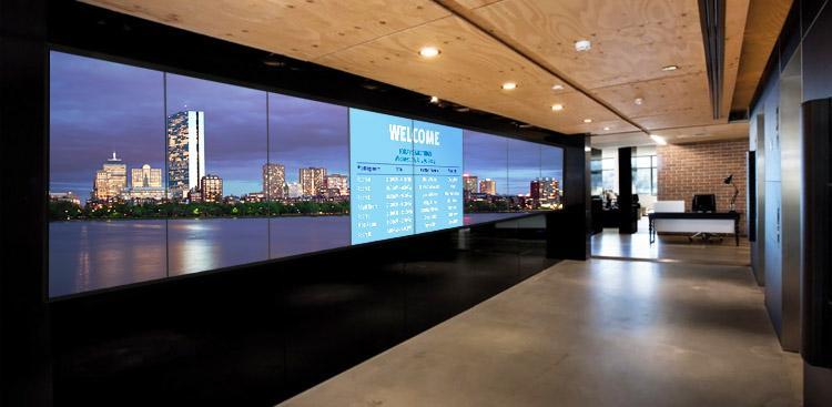Empty office lobby, with a large video wall displaying a welcome banner and photo of a city skyline