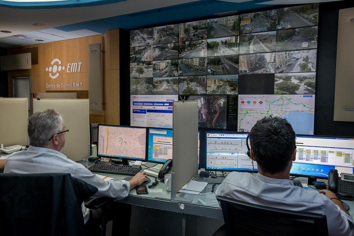 EMT Control Center with workers monitoring transit conditions through their workstations and a video wall displaying transit routes, live footage, and data