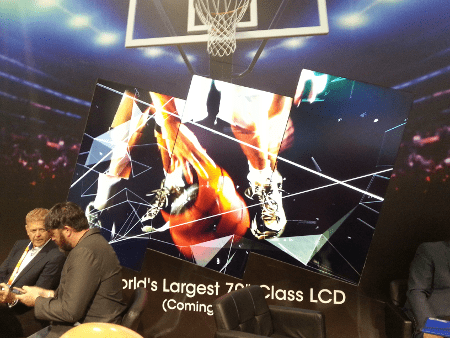 Two people talking in front of an artistic video wall where the screens are on angles and seamlessly showing an image of someone playing basketball.