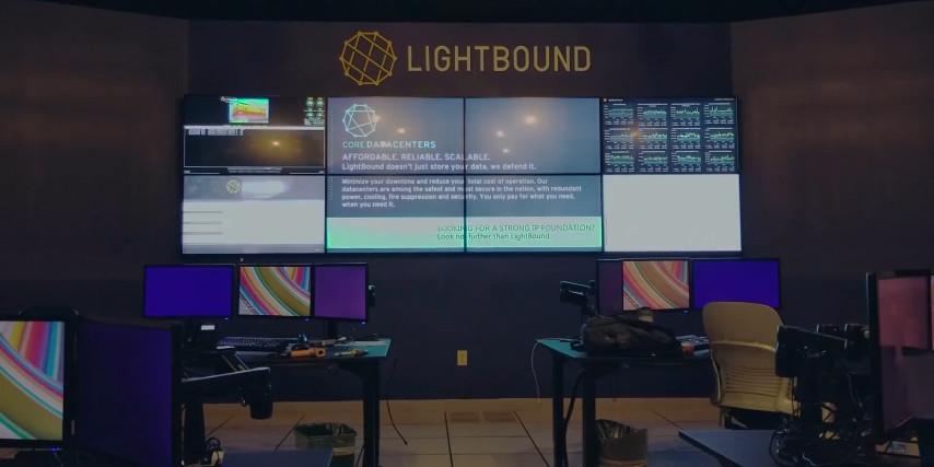 Empty Lightbound control room with 2 workstations and video wall displaying websites, data, and advertisement