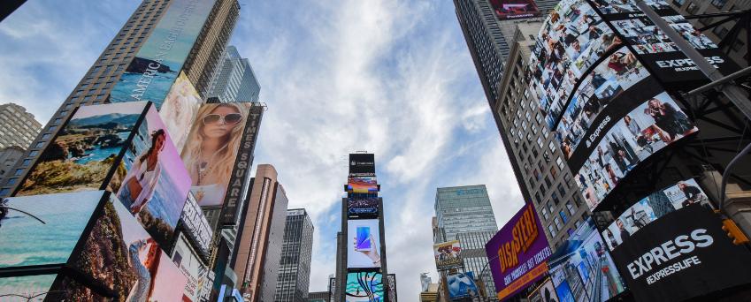 New York City's Times Square filled with video walls and digital signage, and many people in the daytime