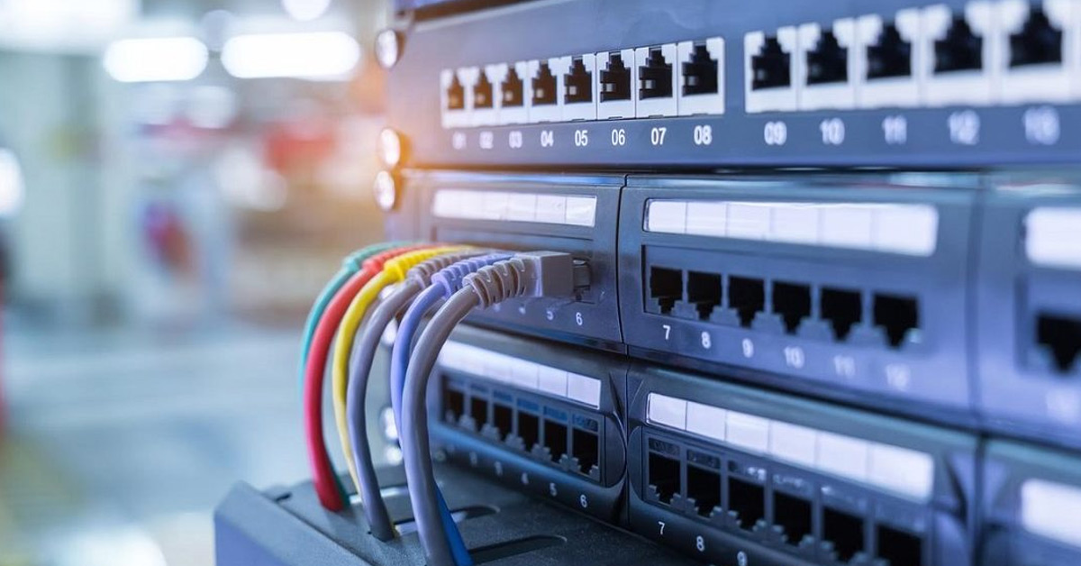 Close up of an ethernet switch with 6 differently coloured ethernet cables plugged into it