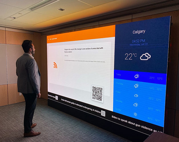 Business man watching news alerts and weather forecast on an office video wall