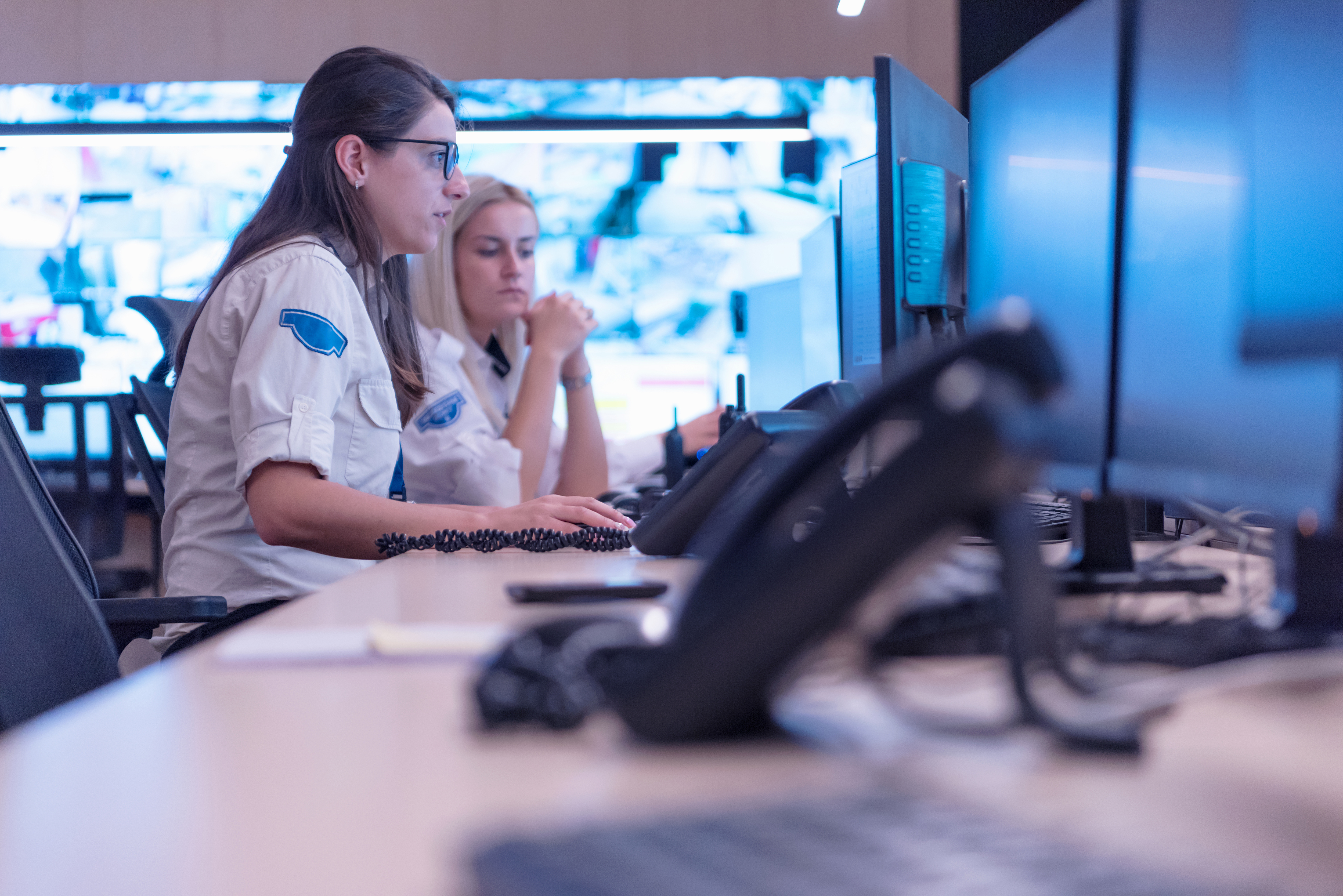 workers in a control room looking at screens and ready to receive calls as they come in