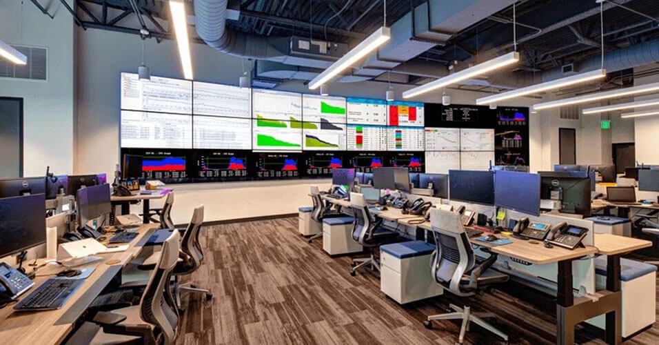 Empty SpectrumVoIP Network Operations Center with many workstations and a larger video wall displaying data dashboards